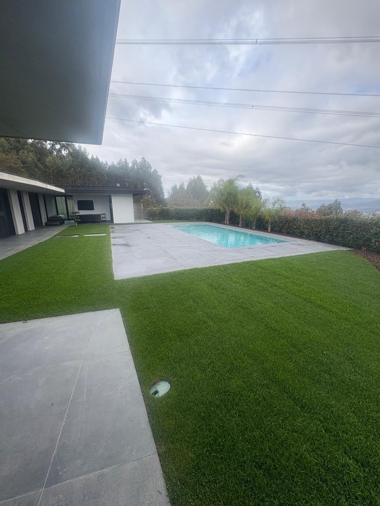 Zona exterior de moradia com relvado, passeio em placas e piscina ao fundo